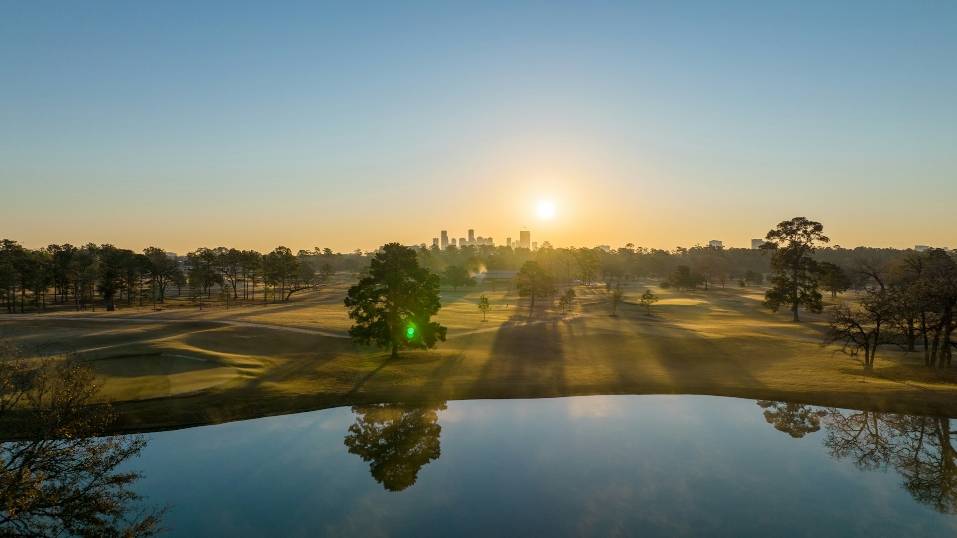 the sun is setting over a golf course